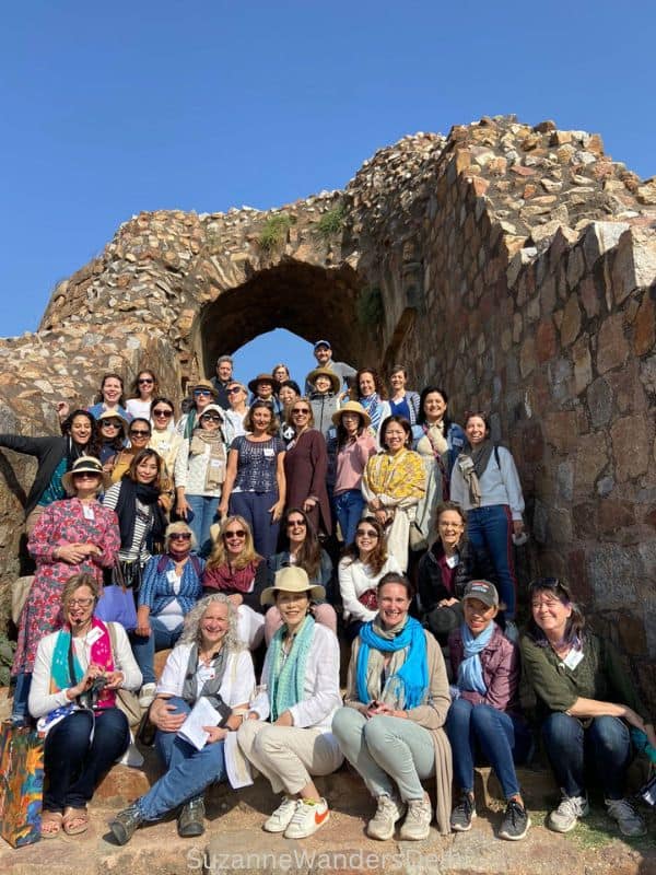 large group of international women sitting and standing on steps with ancient stone arch over them at a Seven Cities group tour, one of the best social networks in Delhi for expats