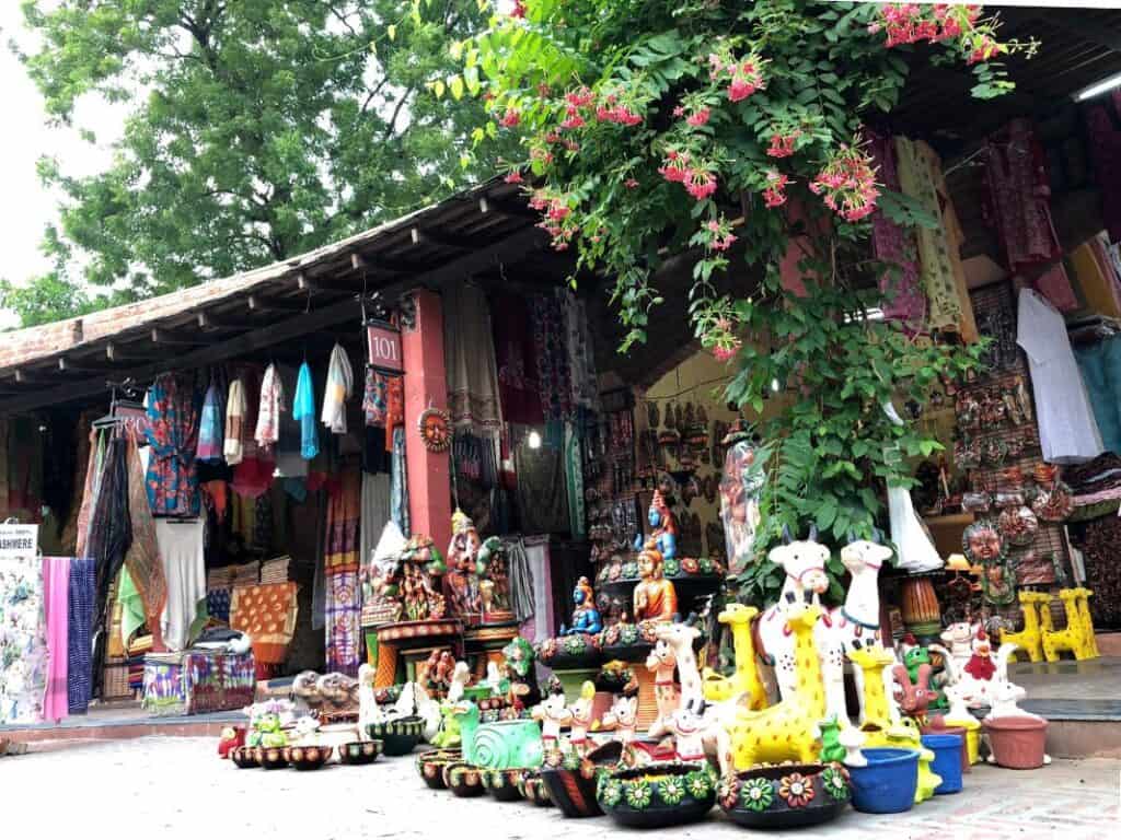 two shops in Dilli Haat, Delhi with flowering vines and crafts on display, a good spot to buy souvenirs and gifts