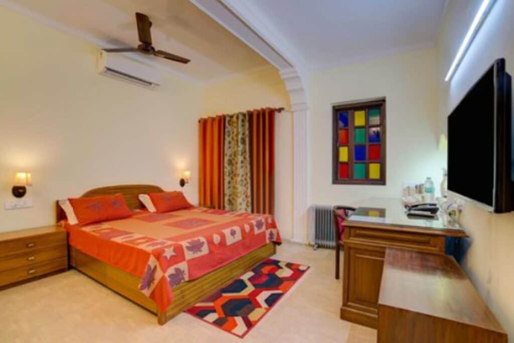 Guet room with large bed and red bed spread, room with wooden desk and side table at CP Villa Bed & Breakfast, the best budget hotel in Connaught Place, Delhi