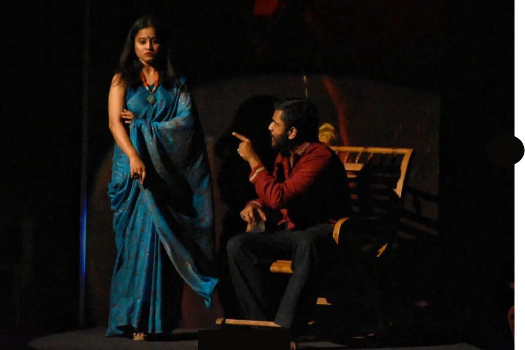 A female actor in blue sari and male actor sitting in a performance by Little Theatre Group in Delhi
