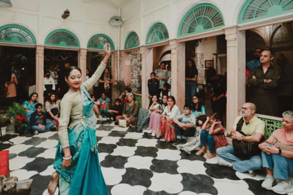 A kathak dance in cream and bue saree performing in old haveli with black and white tiled floor