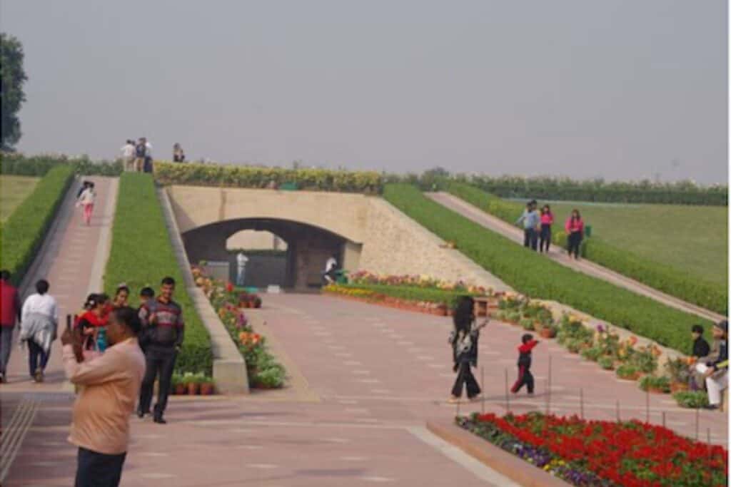 the elevated walkway of Raj Ghat with flowers and Indian people walking