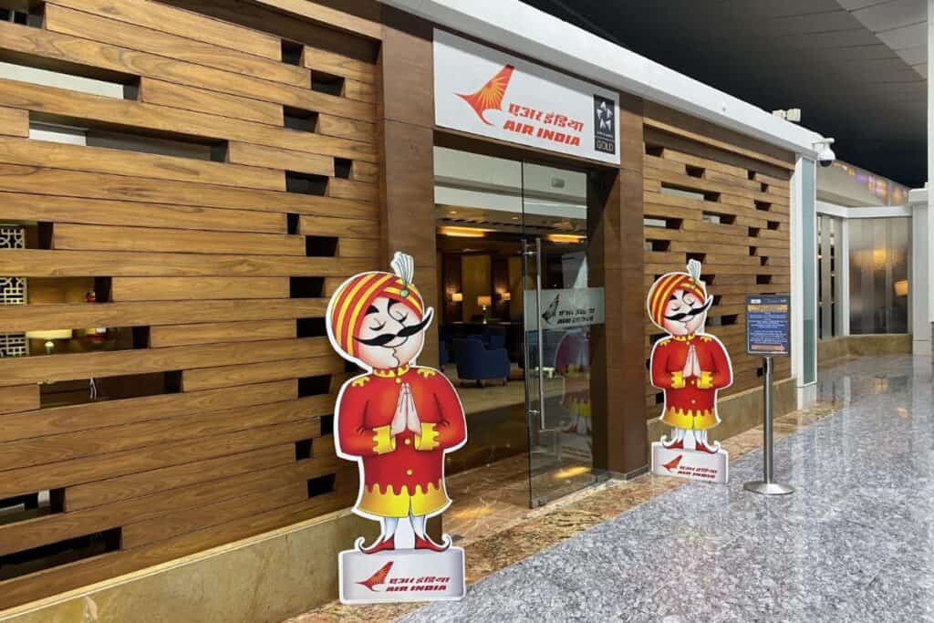 Entrance to Air India Maharaja Lounge in Delhi airport with wood paneling and two Maharaja cartoon characters on either side of the door
