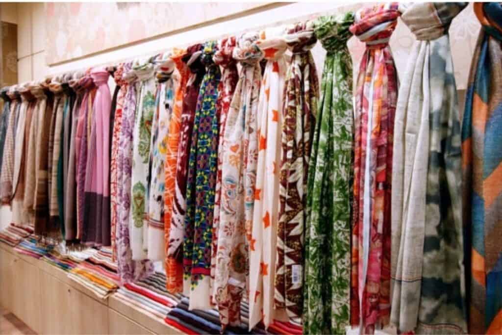 A large selection of pashmina scarfs hanging side by side on a display wall at Shaw Brother in Delhi