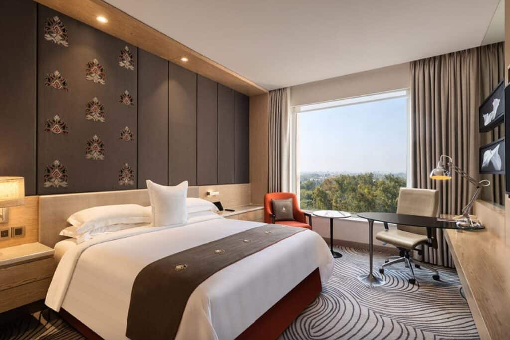 Guest room at the Sheraton New Delhi in hues of brown, a good location to visit the Iron Pillar of Delhi from