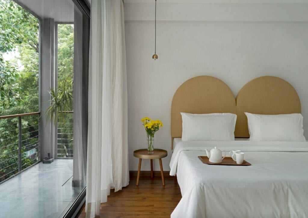 A bright guest room with white linen at Bungalow 157, of the best South Delhi hotels