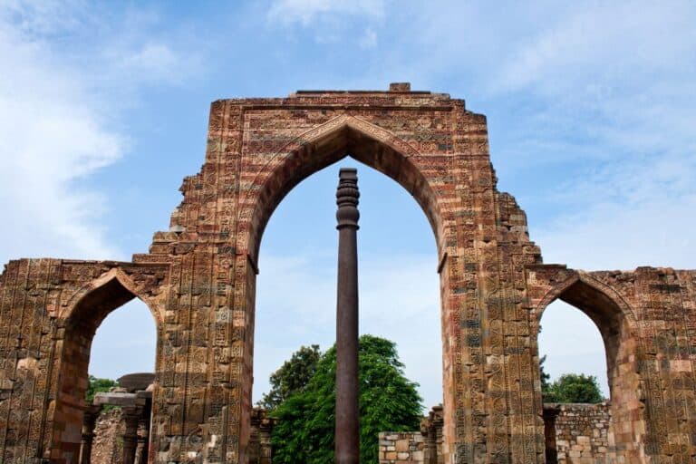 the iron pillar at Qutub Minar in the middle of ancient archway