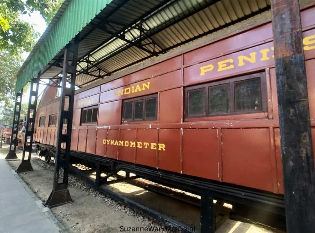 a red dynamometer carraige outside at the Delhi rail museum