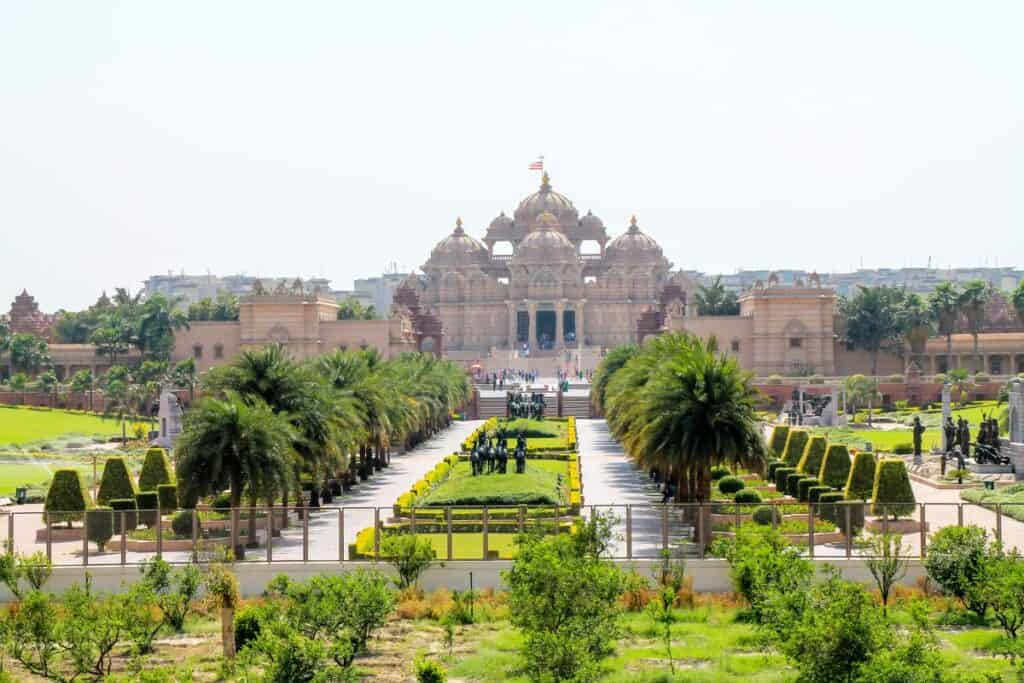 long view of Akshardham Temple with gardens and rows of palm trees