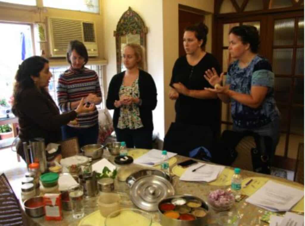 5 women standing around a table taking a cooking class in a Delhi home