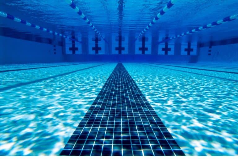 inside the water of a swimming pool with blue tiles