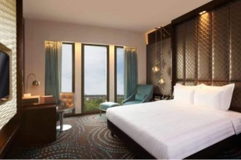 Room with brown carpeting and large king size bed at Pullman New Delhi Aerocity, one of the luxury hotels near the airport