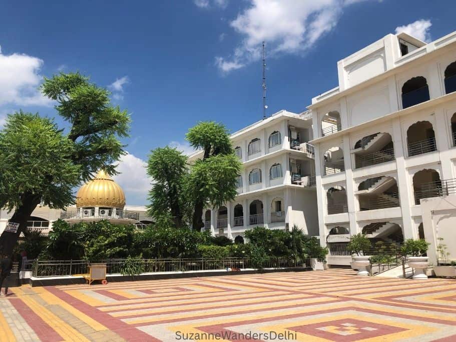 two white buildings on large courtyard at Bangla Sahibi in Delhi