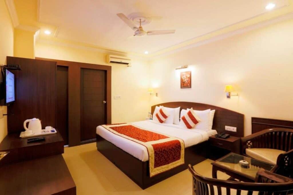 Roomwith double bed and dark wood furniture at La Sapphire Hotel in Delhi
