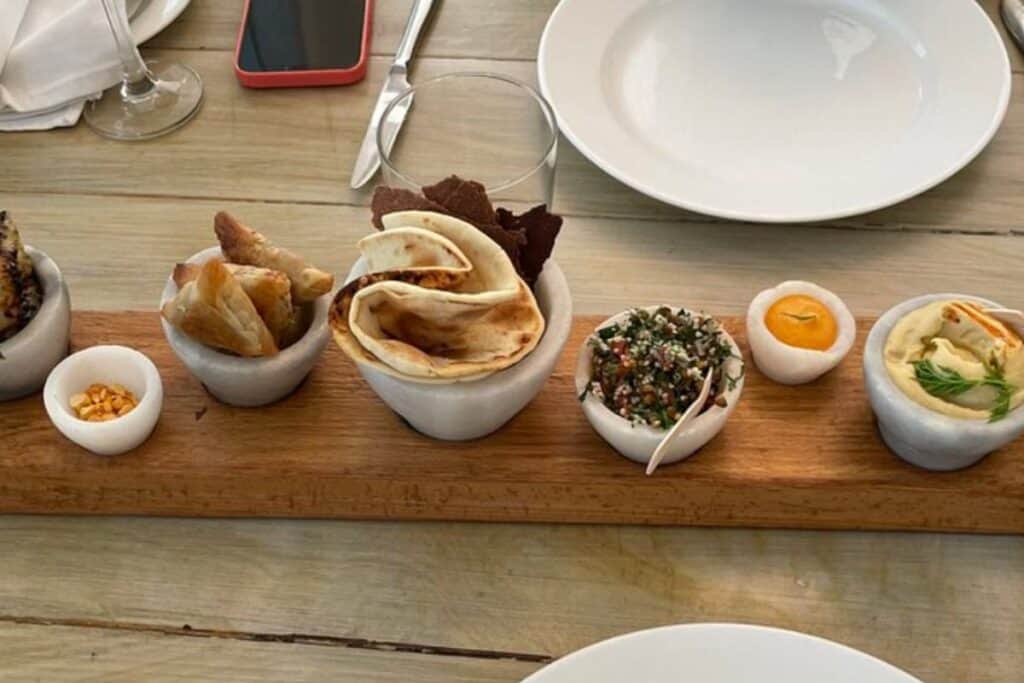 long meze wooden meze platter with white bowls filled with meze at Olive Bar and Kitchen