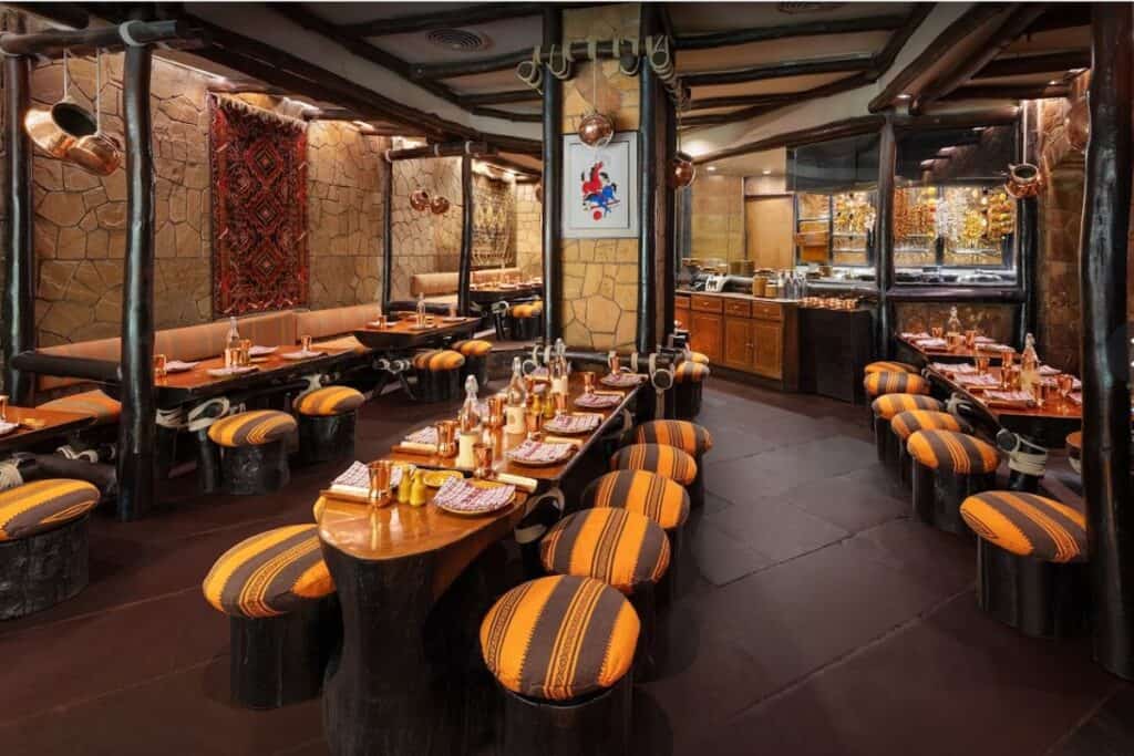 the dining room at Bukhara with striped stools and long wooden tables, a unique dining experience for foodies in Delhi