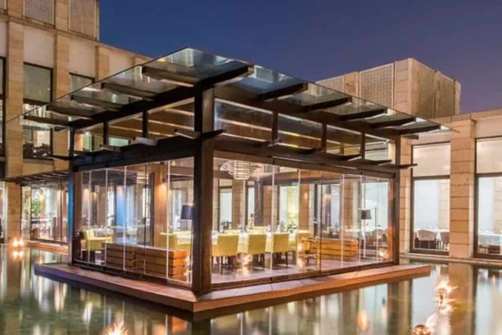 Exterior view of Indian Accent, encased in glass walls with a pool surrounding it