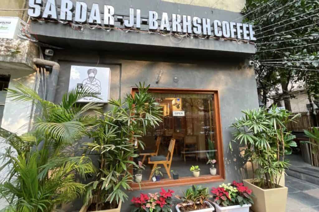 Exterior or Sardar Ji Bakhsh Coffee in Malviya Nagar with potted plants and flowers in front
