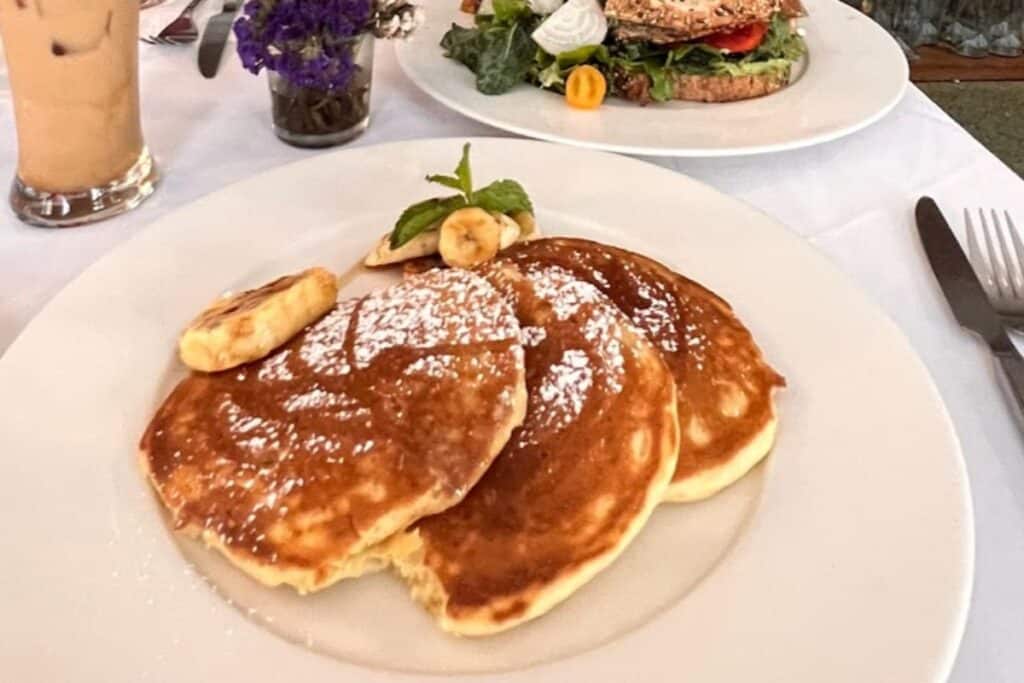 white plate with three pancakes and sliced bananas at CAARA at Oggan, the best breakfast cafe in Delhi