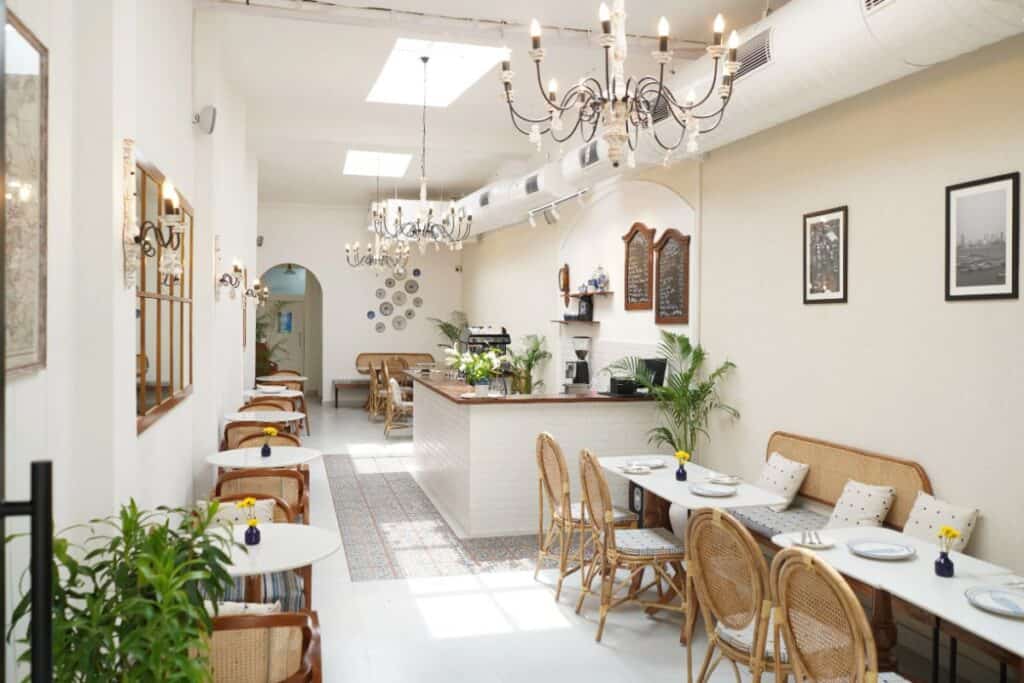 interior of Bombay Club with wicker chairs and white tables set up along white walls