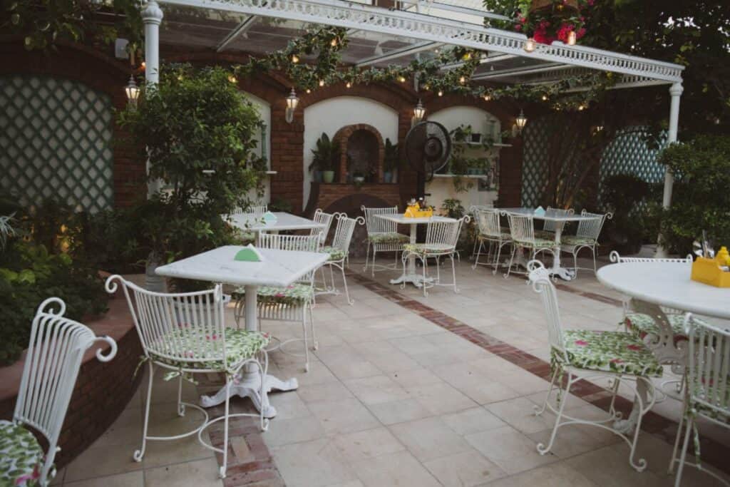 outdoor garden patio with white garden chairs and tables at Diggin in Bikaner House, Delhi