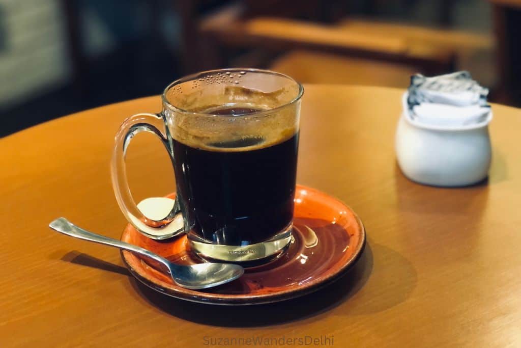 glass cup of coffee on wood table at Tan Coffee, of Delhi's best coffee shops