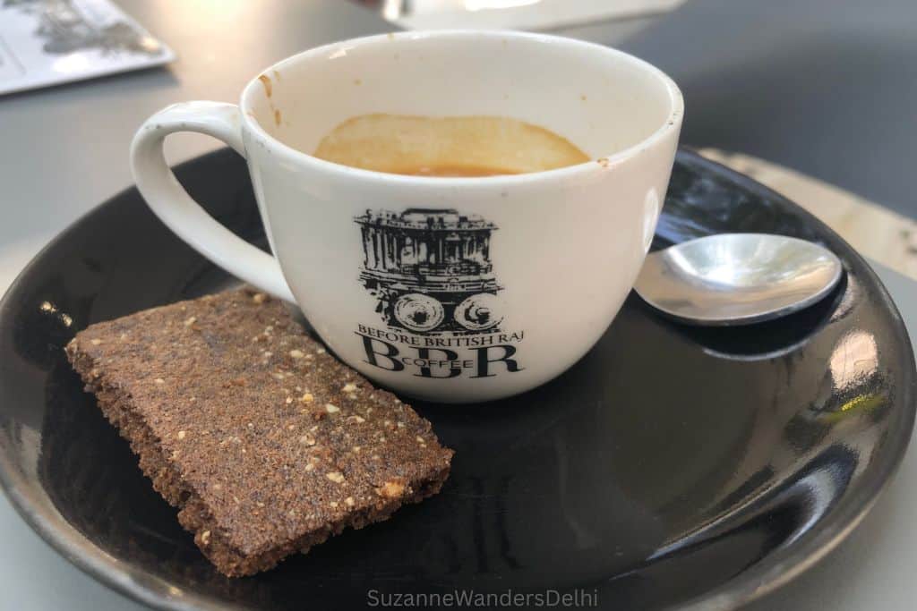 white coffee cup with black BBR logo on black saucer and cookie on the side