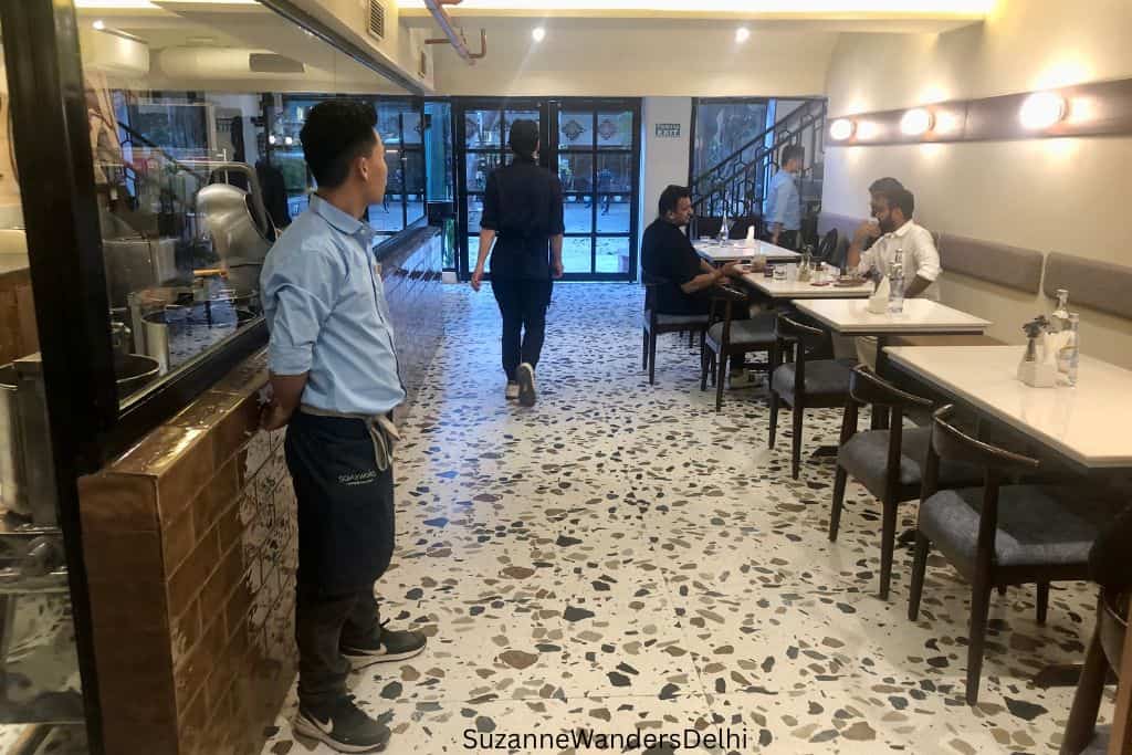 long view of dining room with white tables on right side and waiter on left side