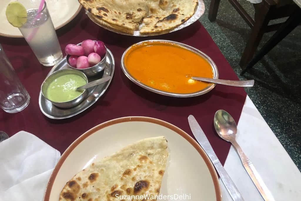 serving of butter chicken and two plates of naan at Moti Mahal in Delhi