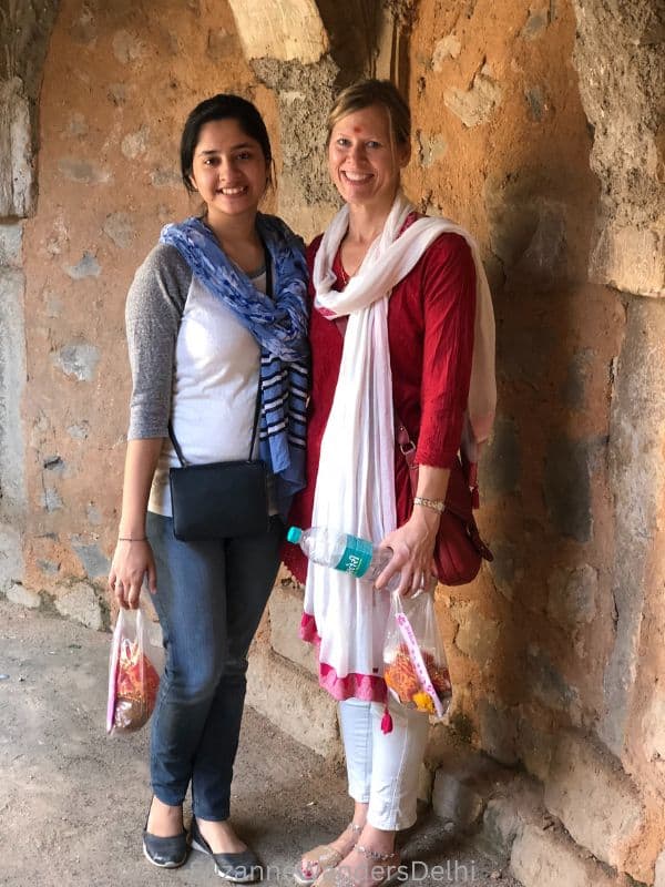 the author and Indian friend wearing dupattas standing and facing the camera holding bags of flowers