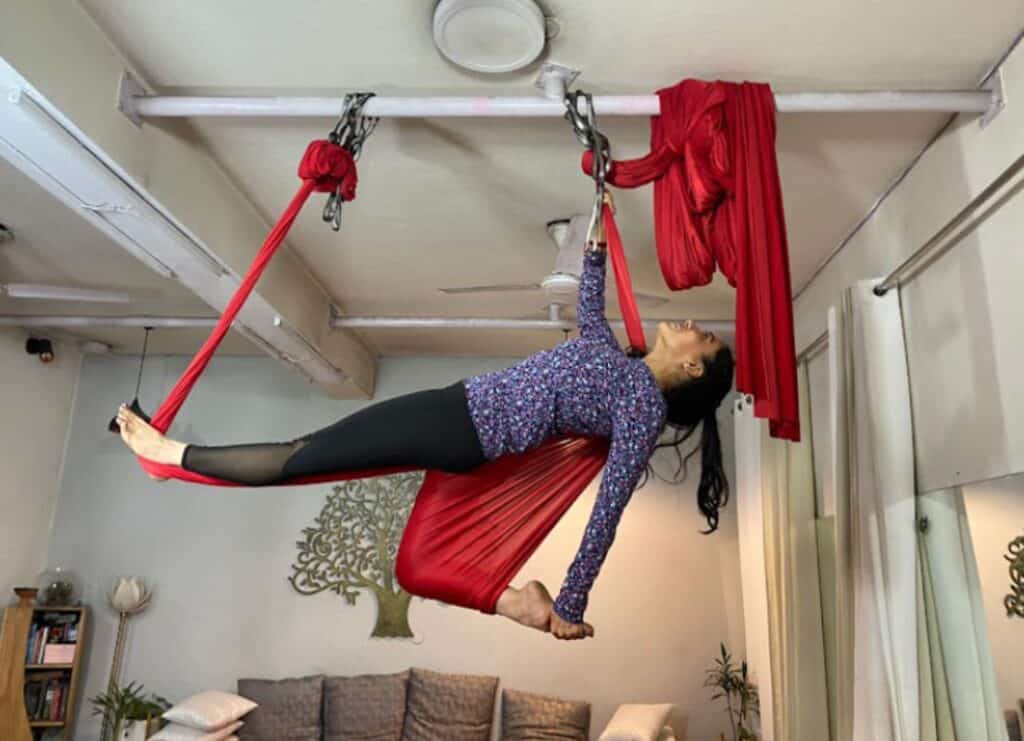 yoga teacher in an elevated asana doing aerial yoga at The Pink Lotus Academia, one of the the best places for yoga classes in Delhi