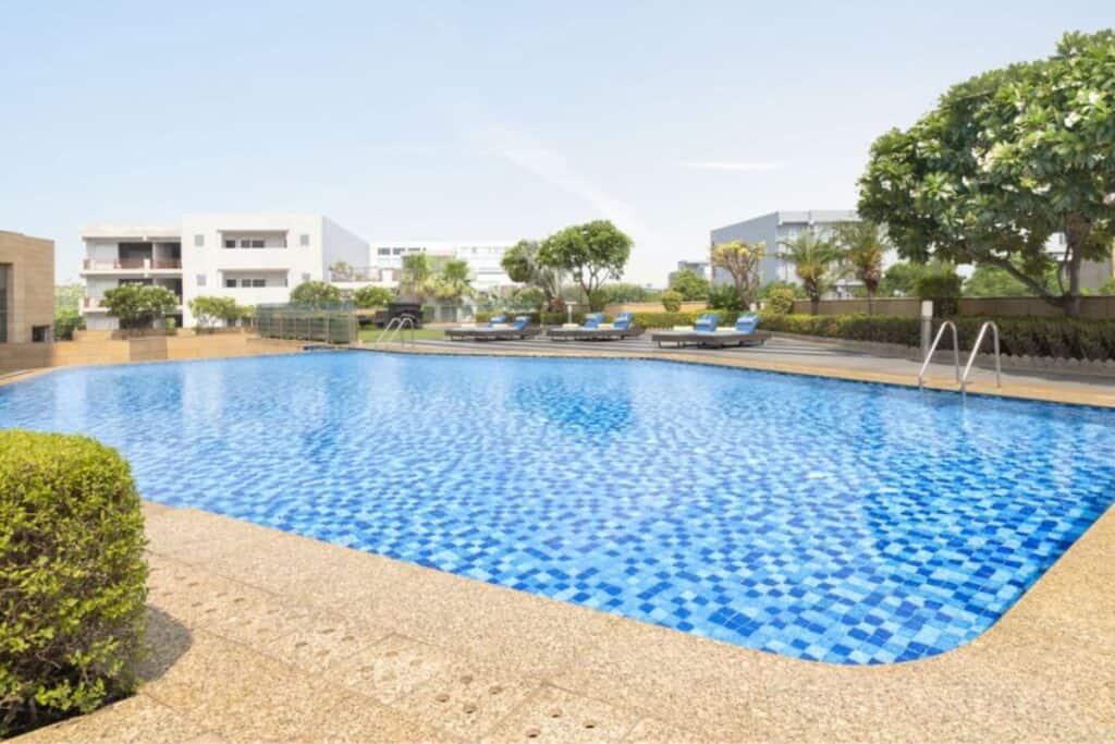 a large outdoor pool with trees and loungers around it