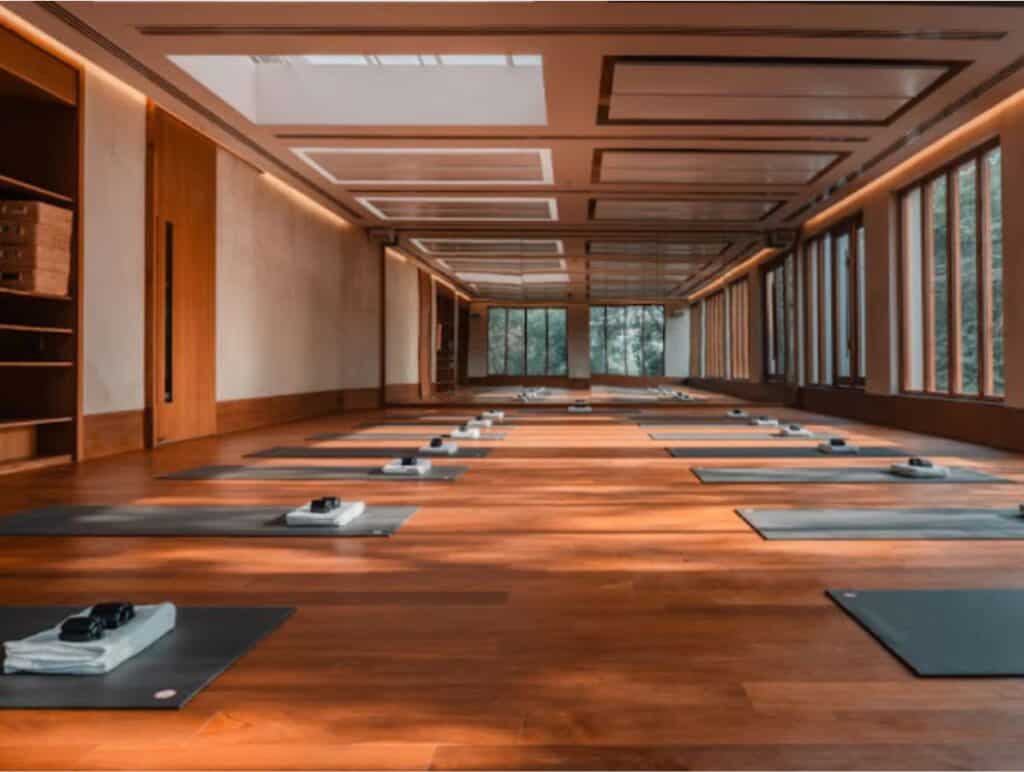 Long view of yoga studio with wood floor ing and grey mats lined up on two sides of room, Delhi's most beautiful studio for yoga classes 