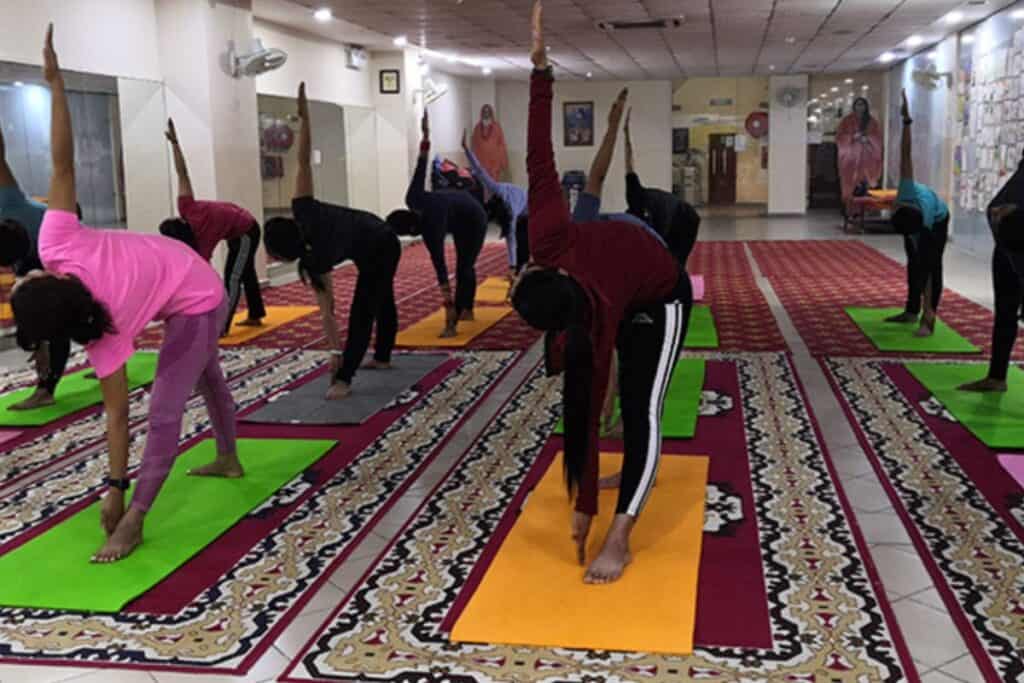 students ding pyramid pose on carpeted yoga studio in Delhi at the Yoga Institute Delhi