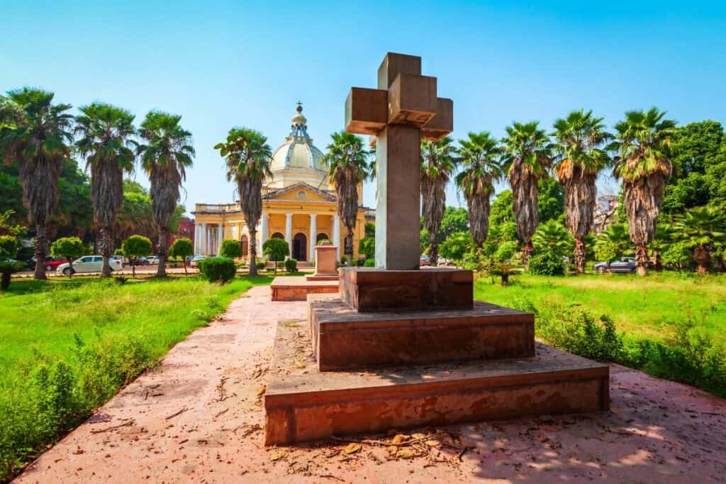 exterior view from across a garden with statue of cross to the most famous church in Delhi, St. James Church