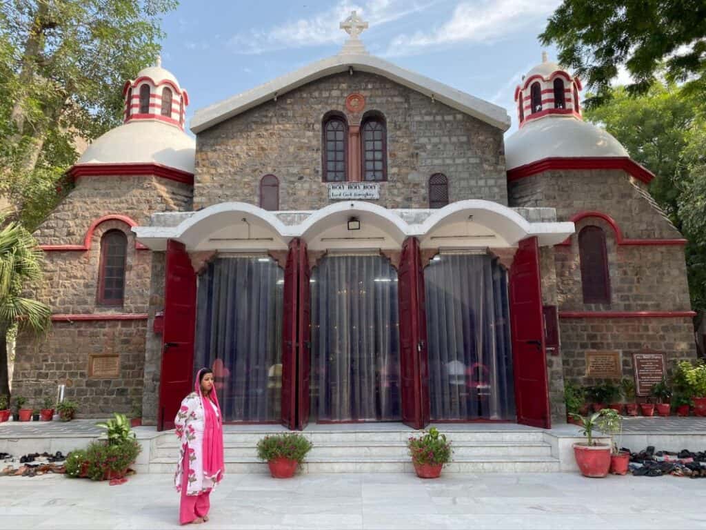 exterior full view of Holy Trinity Church with blue sky and woman in Indian suite standing in front