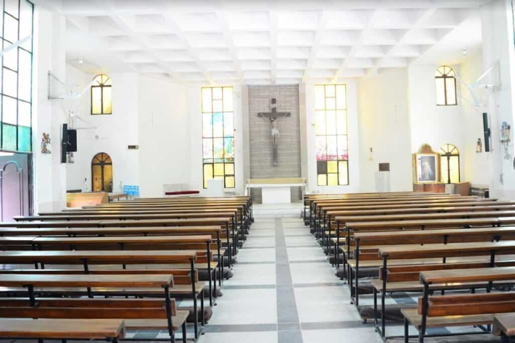 Interior of the famous St. Dominic Church in Delhi with wooden benches and bright white walls and large crucifix in the front