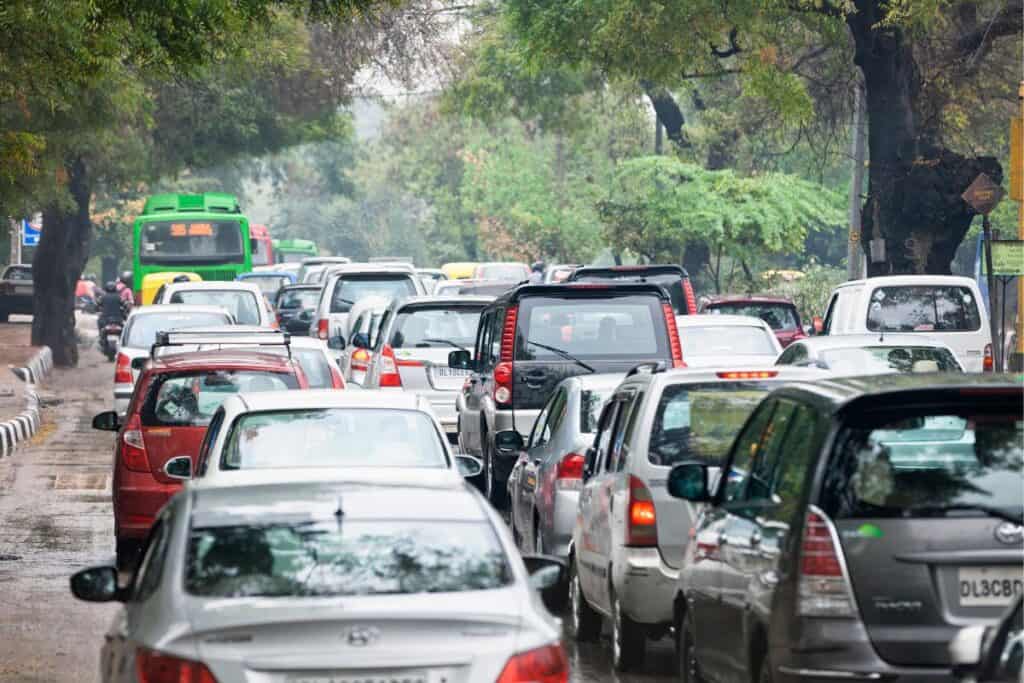 A tree lined street in Delhi full of traffic