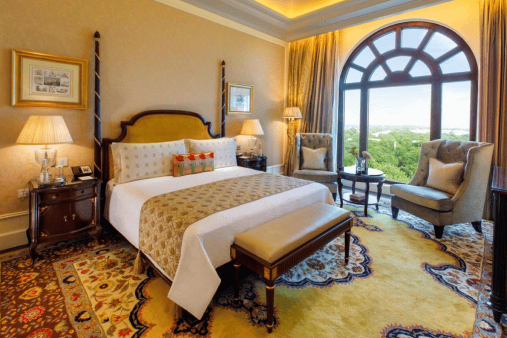 two poster bed in elaborate gold and white beding with gold draperies and Persian style carpeting at Leela Palace in New Delhi, the very best 5 star hotel in Delhi