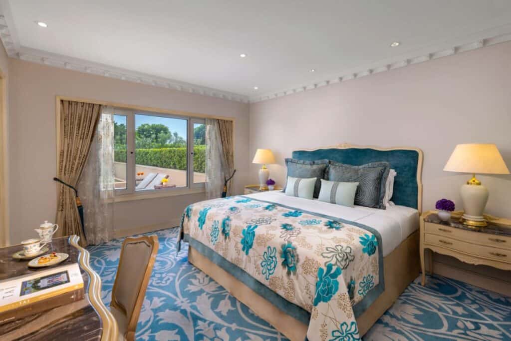 king size bed with blue and cream coloured bedding and blue and off white carpeting in Taj Palace, New Delhi