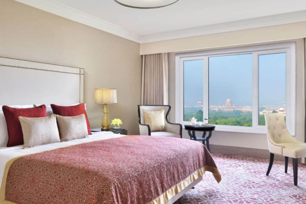 king size bed with red and gold bedding, cream colour wing back chairs and patterned carpting at Taj Mahal hotel, Delhi