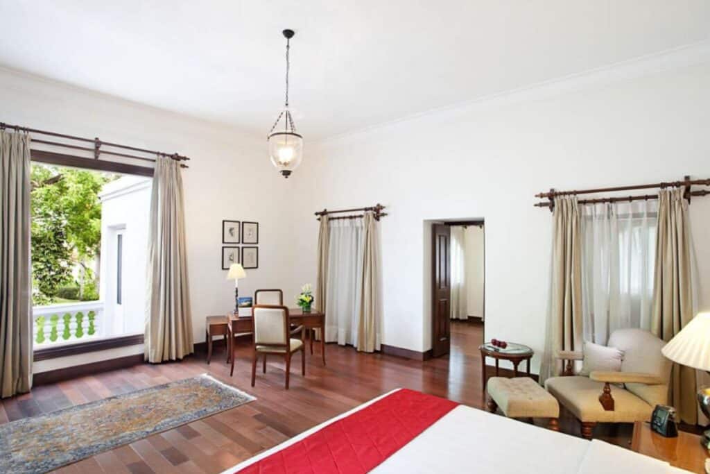 spacious room with white walls and cream curtain and wood floors at Maidens Hotel Delhi, the oldest 5 star luxury hotel in Delhi