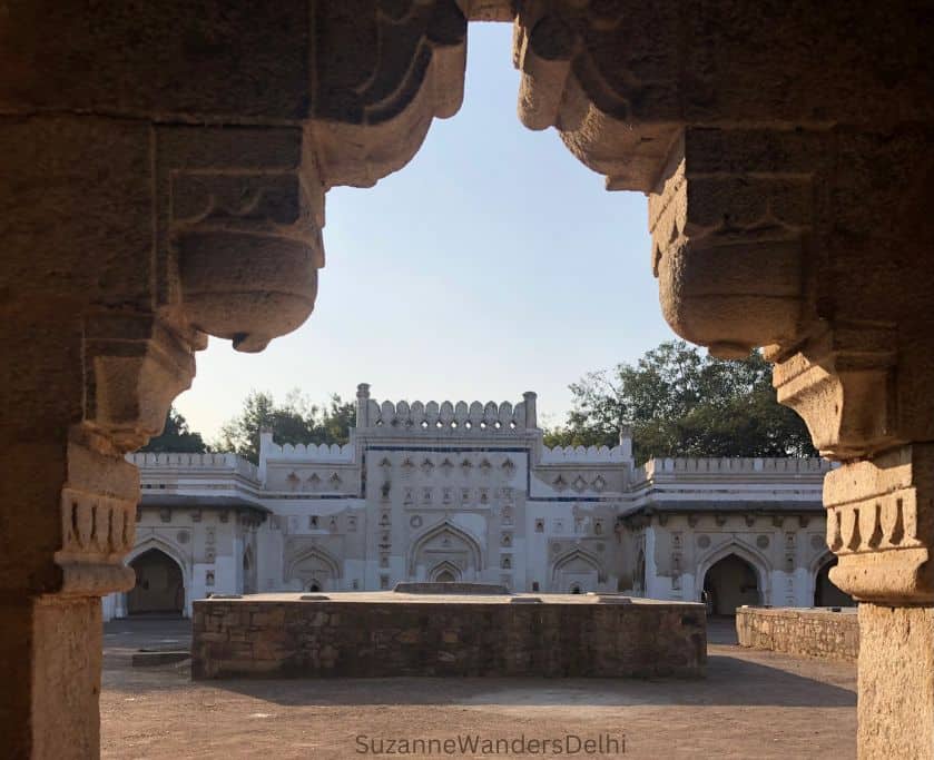 looking through stone archway to white washed Madhi Masjid in Delhi