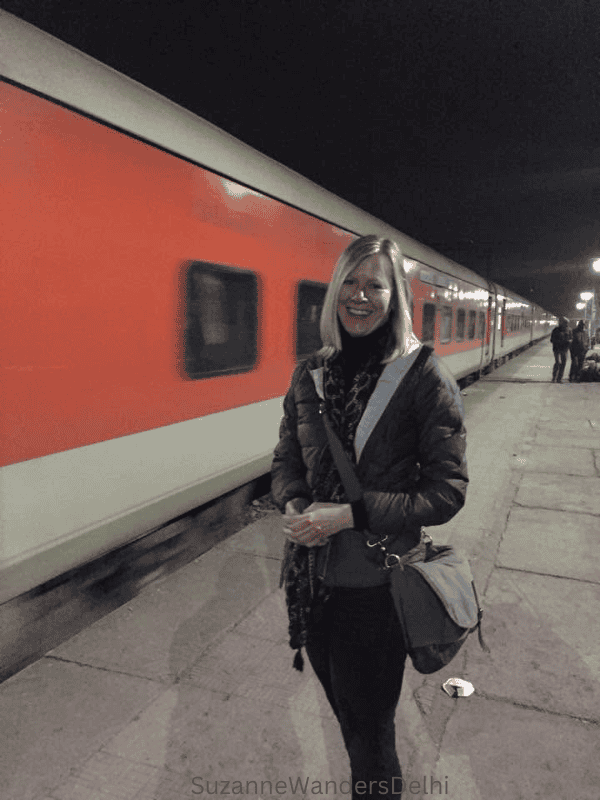 the author on the train platform with red train beside her with train ticket in hand to Delhi