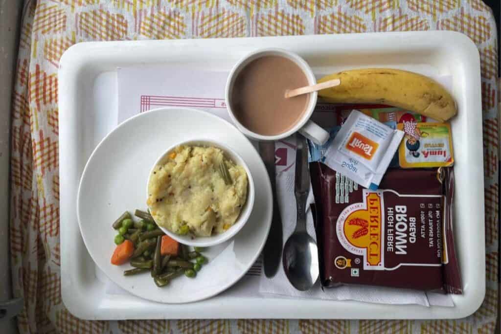 Indian breakfast food with chai and a banana on a tray on Rajdhani Express train 