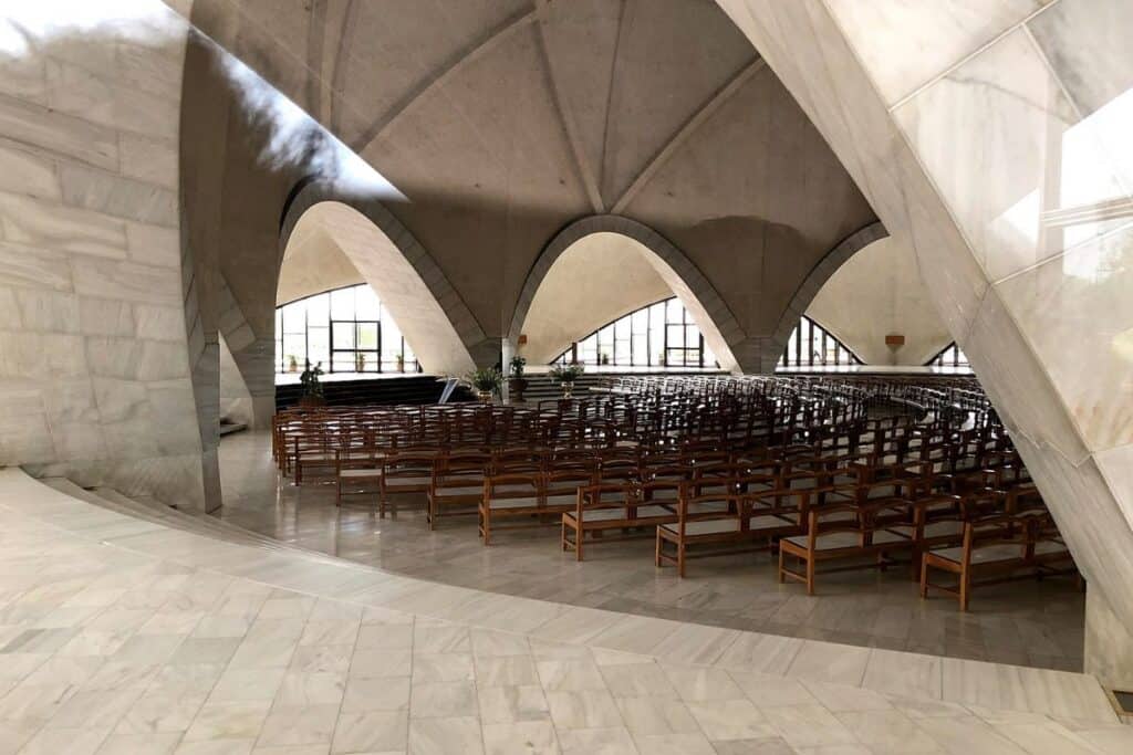 the pale marble interior of the prayer hall at Bahai Lotus Temple  with rows of benches for seating