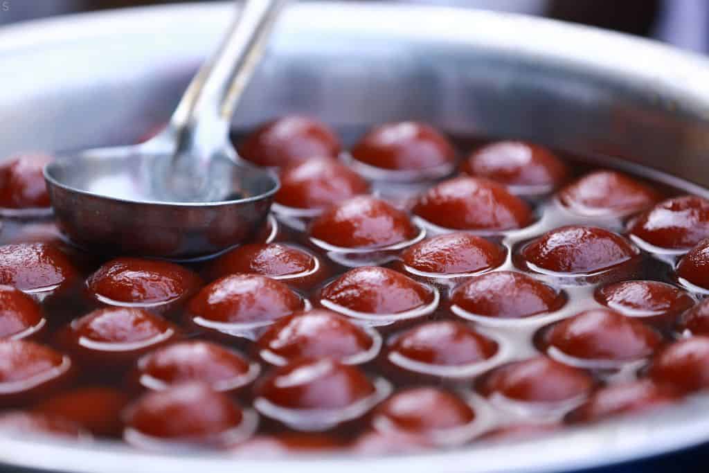 a vat of gulam jamun floating in syrup, the most famous sweet in Delhi