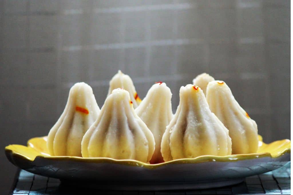 7 modak with saffron garnish on a yellow plate