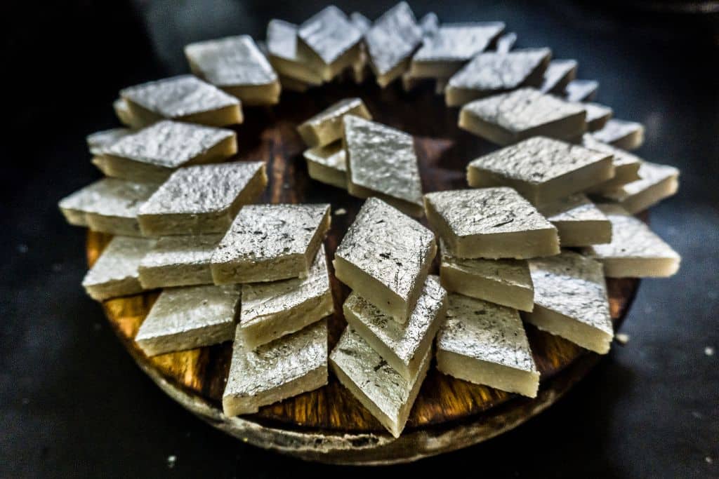 a stack of diamond shaped kaju barfi with silver foil