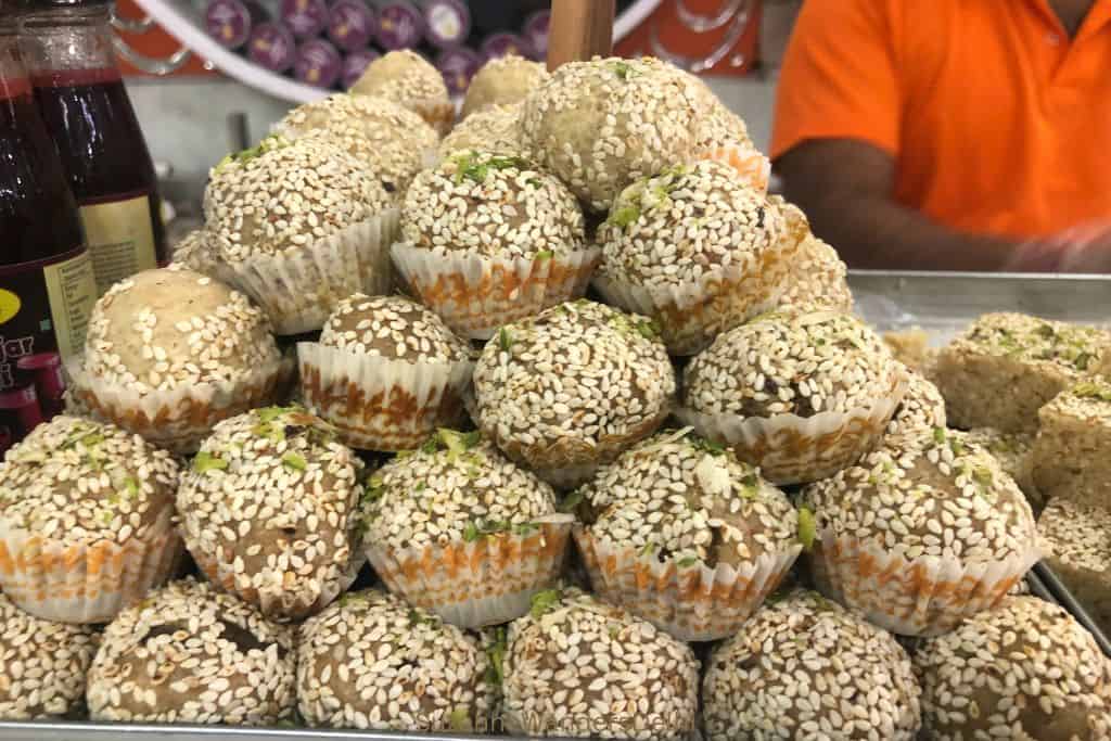 stack of ladoo coated in sesame seeds at Moti Sweets in Delhi